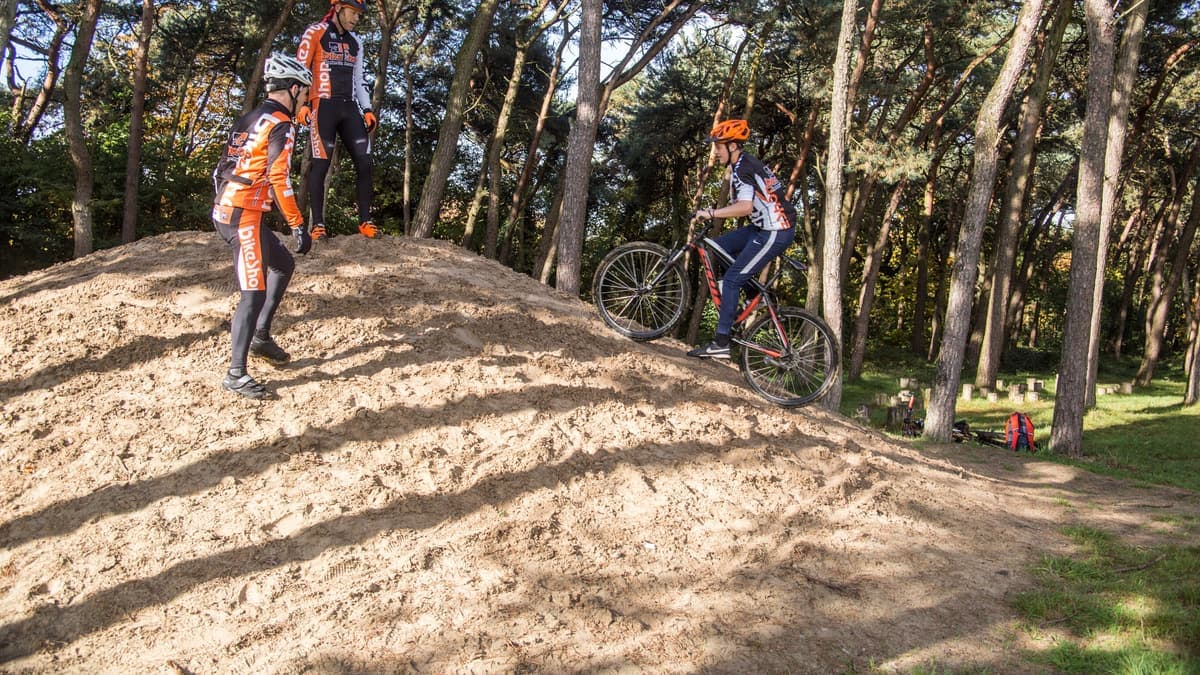 Mountainbikers op een zandheuvel tussen de naaldbomen op de Galgenberg