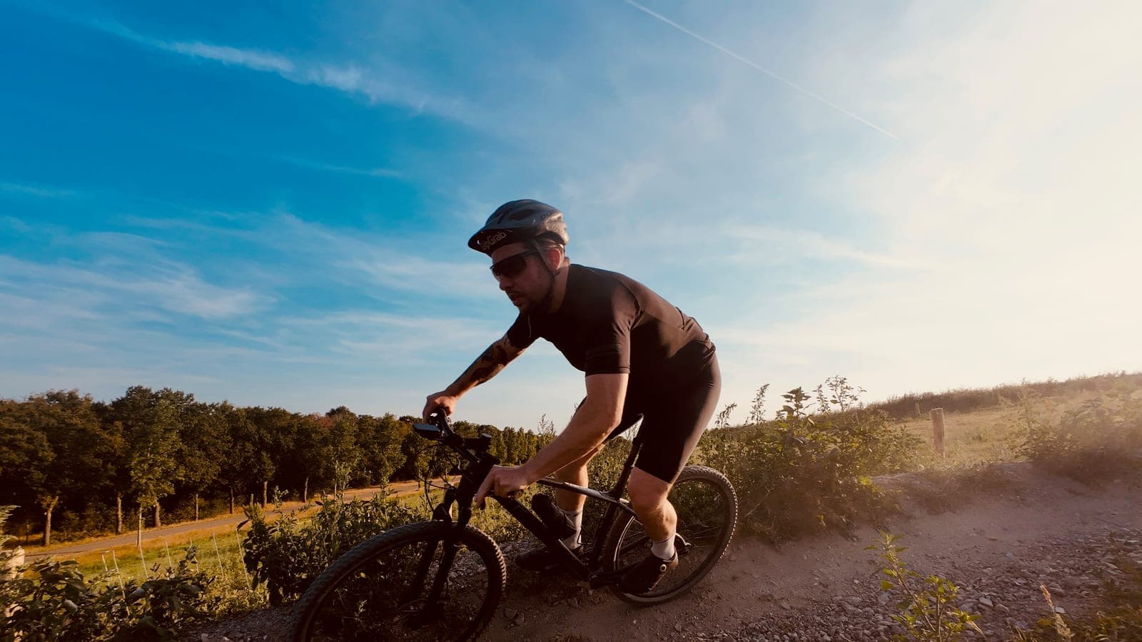 Mountainbiker in een bocht over grind in laagstaande avondzon